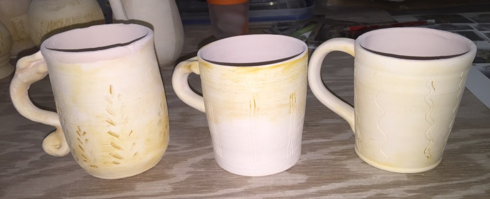 Pig Iron Glaze on three pottery mugs ready to be wood-fired.